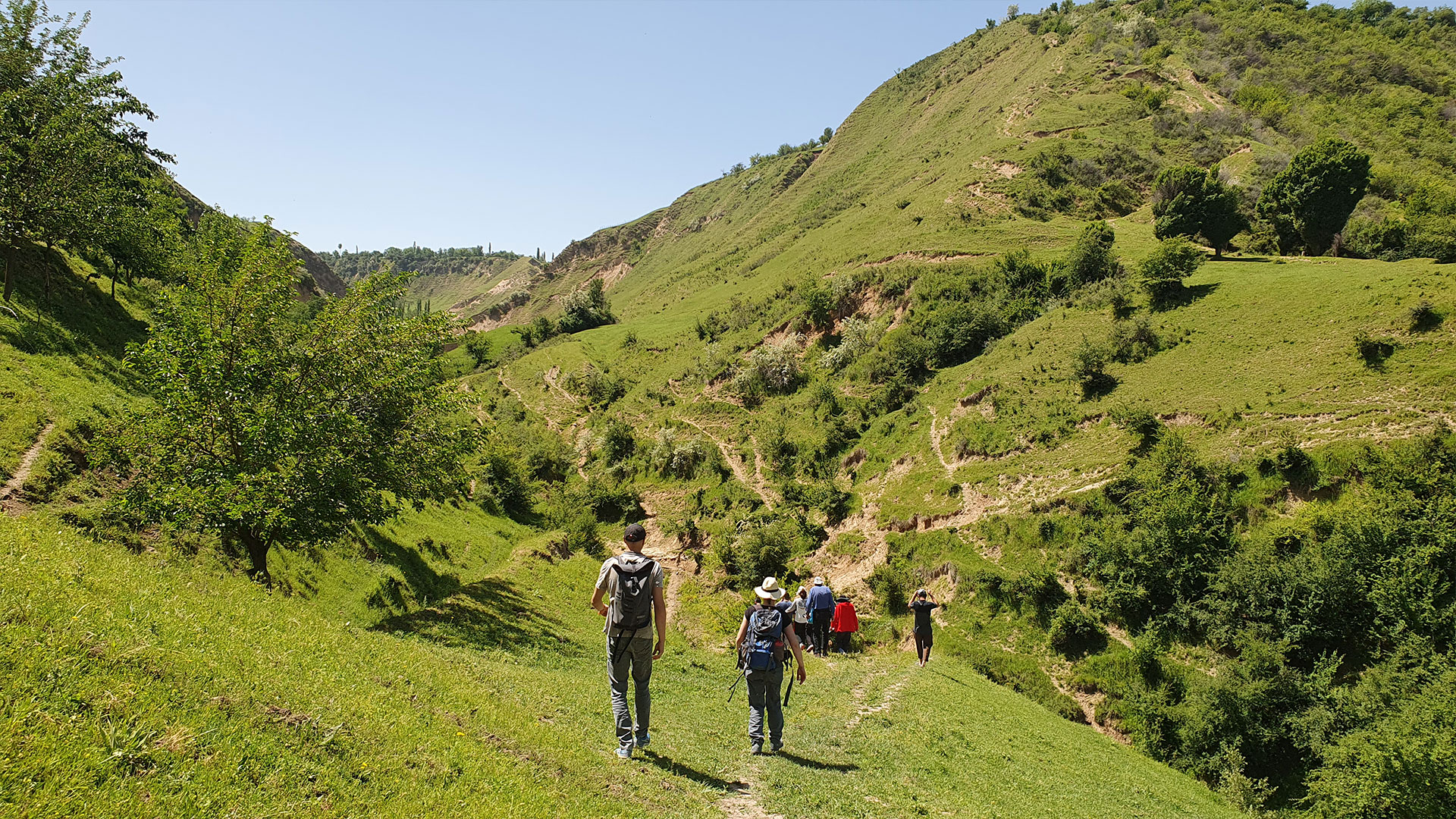 Mennesker går gennem grønt landskabet i Khovaling regionen i Tajikistan. Foto: Miriam Meister